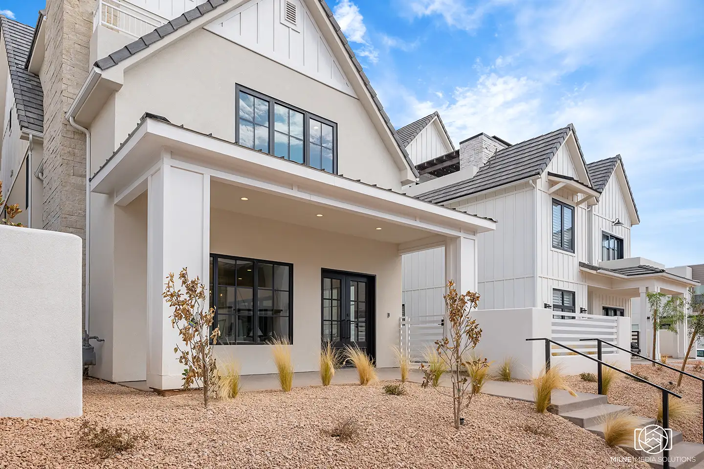 Front exterior of a white modern farmhouse-style luxury home with desert landscaping.