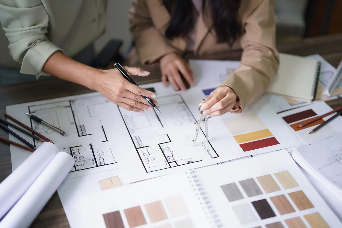 Two people reviewing architectural floor plans with color and material samples during design planning.