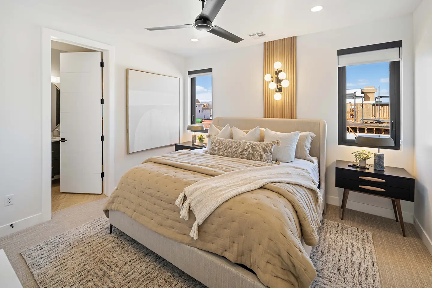Guest bedroom with an upholstered bed, midcentury nightstands, a sputnik sconce and windows overlooking the neighborhood.