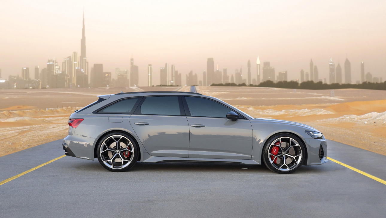 Silver Audi RS6 Avant on desert road with Dubai skyline background