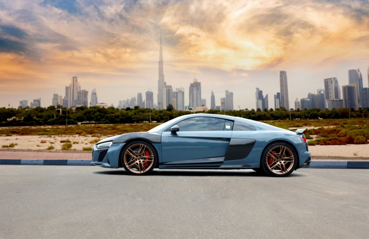 Blue sports car parked with Dubai skyline and Burj Khalifa in background