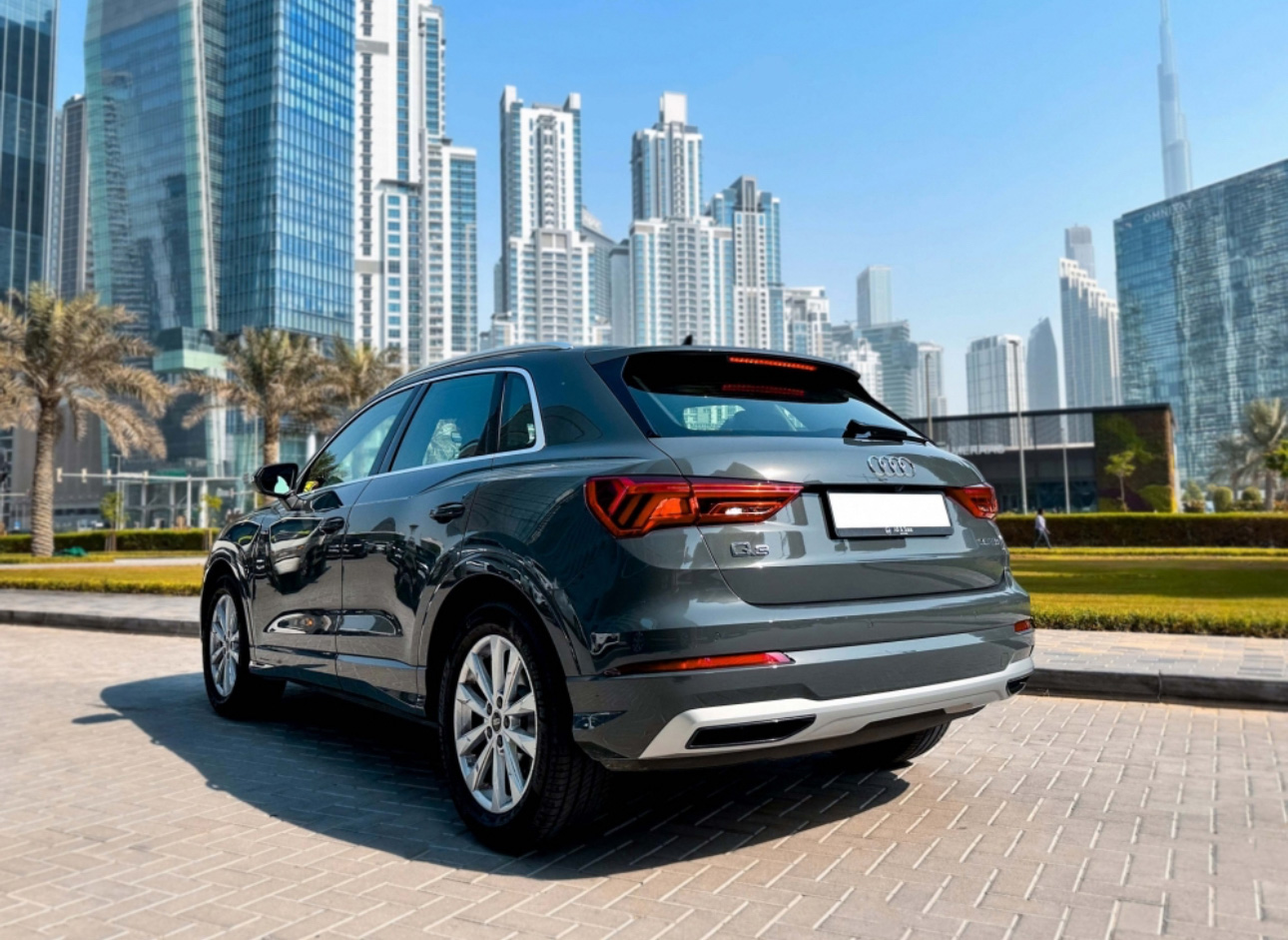 Black Audi Q3 parked in modern Dubai cityscape with skyscrapers