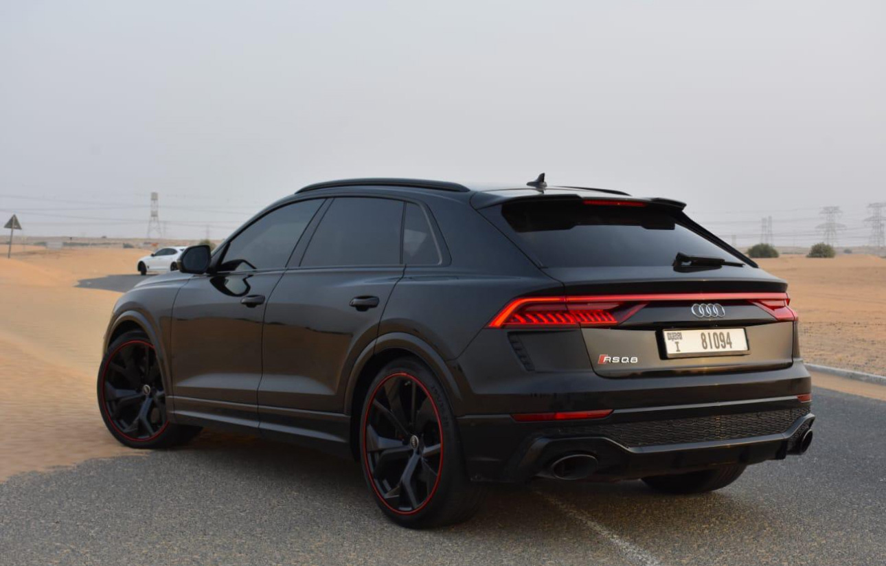 Black Audi RSQ8 SUV with red-rimmed wheels parked in desert landscape
