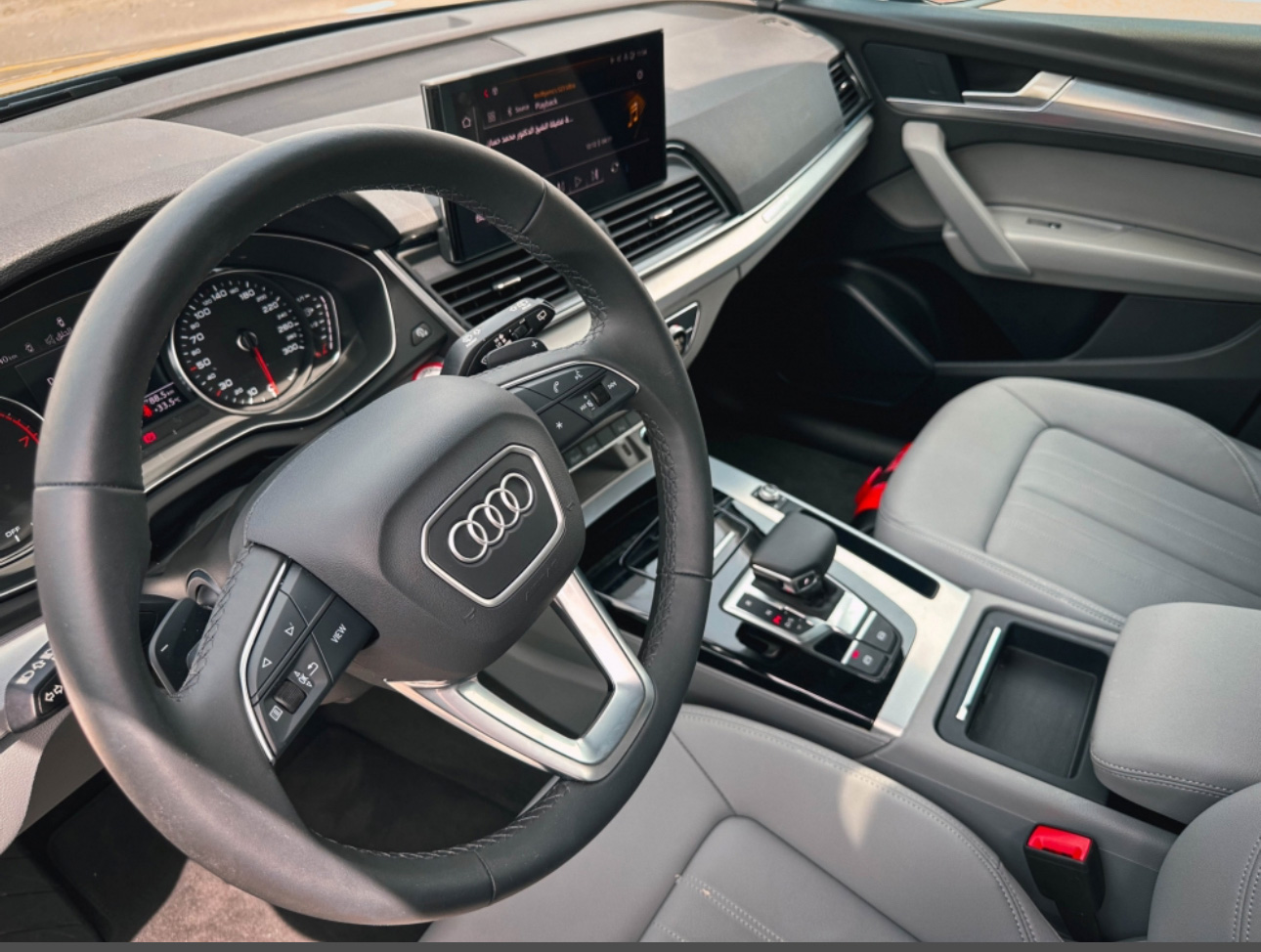 Interior of an Audi vehicle with steering wheel, dashboard, and infotainment screen