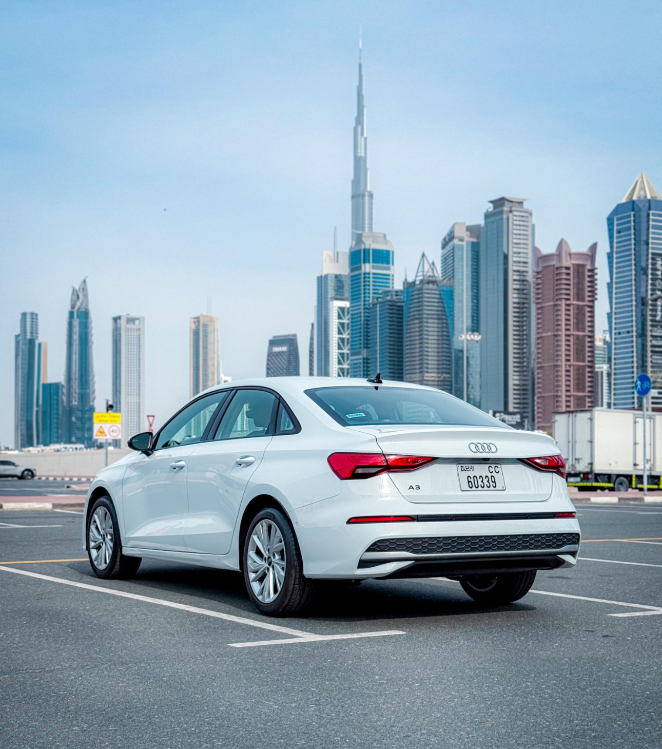 White Audi A3 parked with Dubai skyscrapers and Burj Khalifa in background