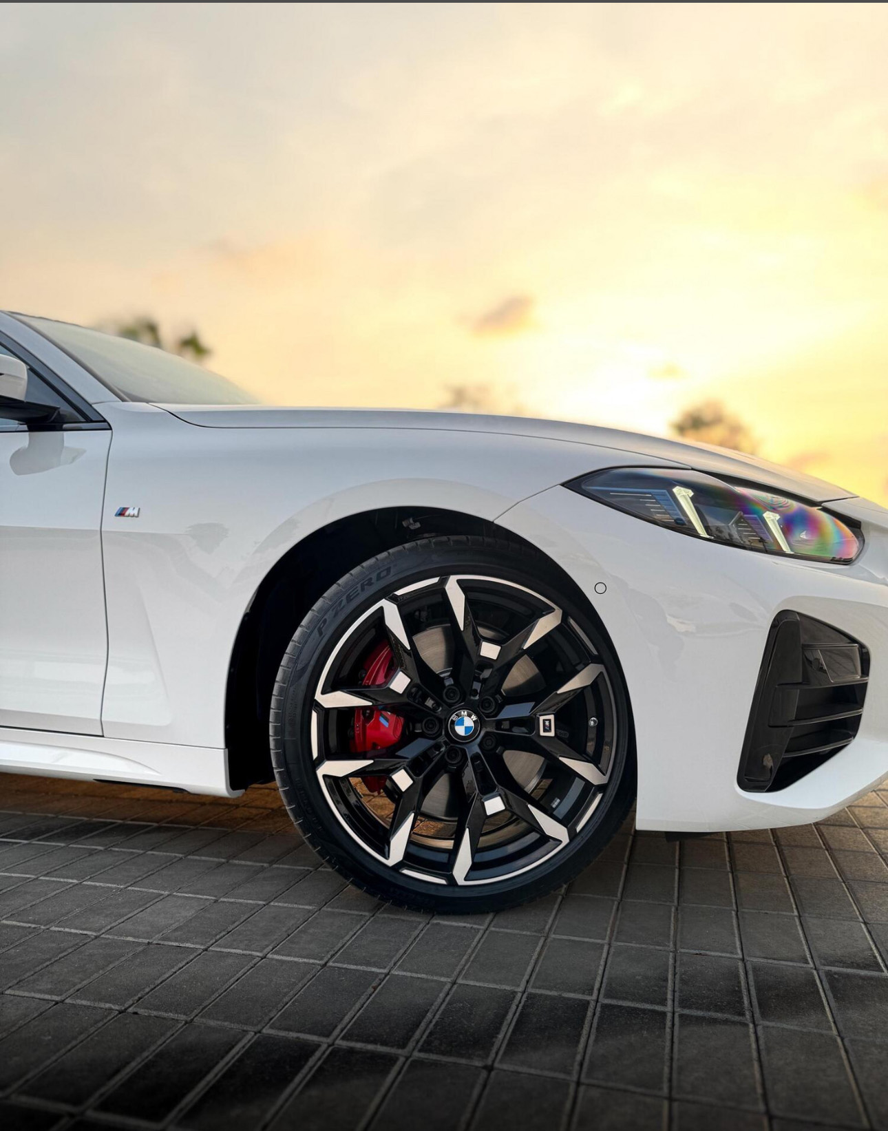 White BMW with stylish alloy wheels parked at sunset
