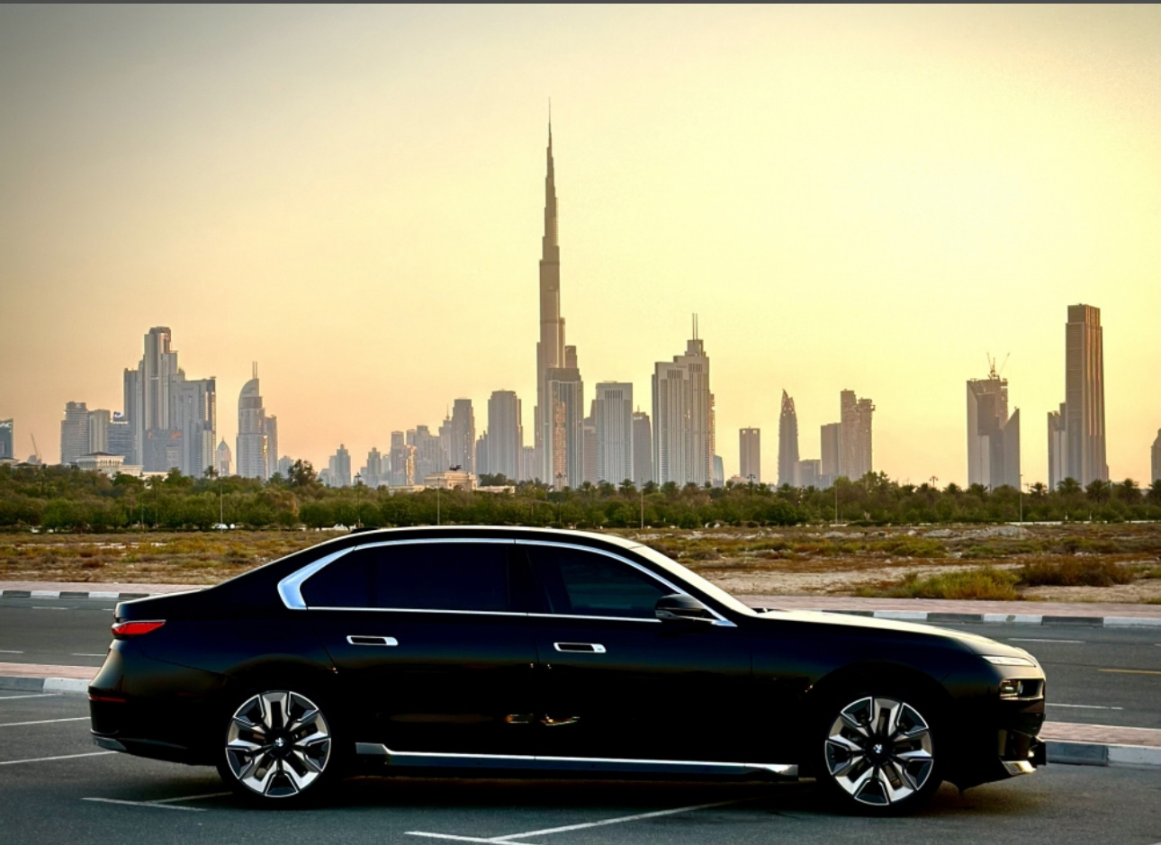 Black luxury car parked with Dubai skyline and Burj Khalifa at sunset
