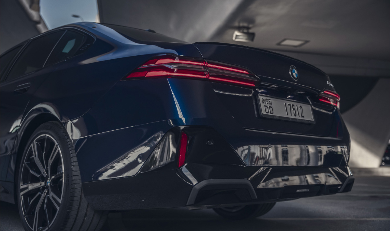 Sleek black BMW with red taillights parked in a dimly lit interior