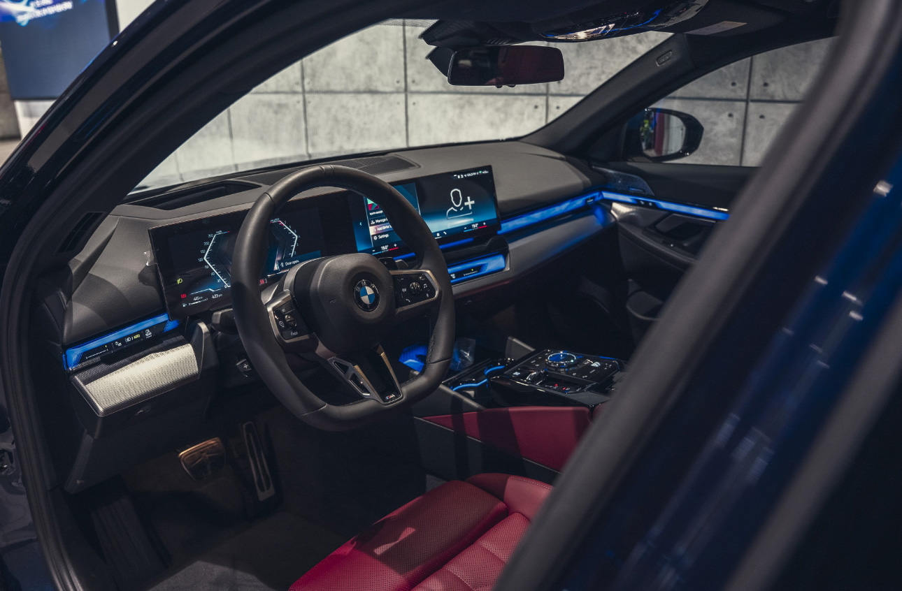 BMW interior with digital dashboard, blue ambient lighting, and red seats