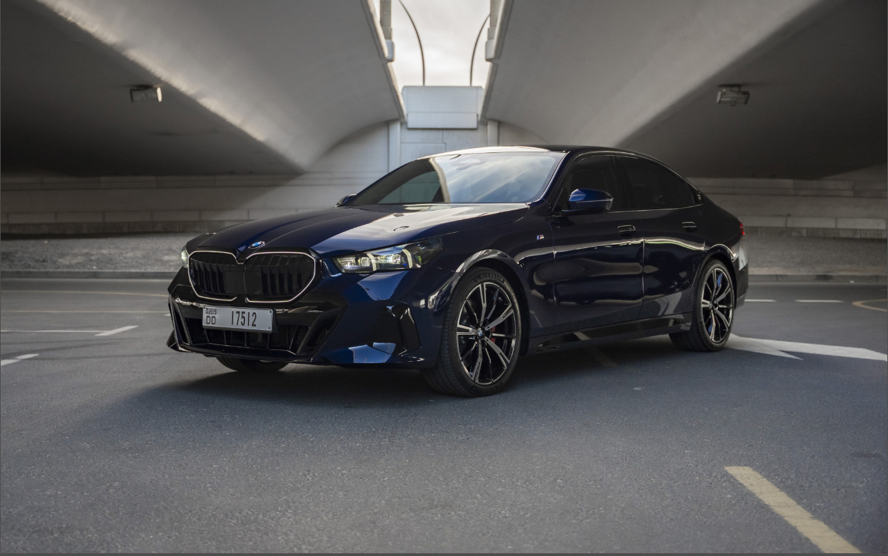 Dark blue BMW sedan parked in modern concrete parking structure