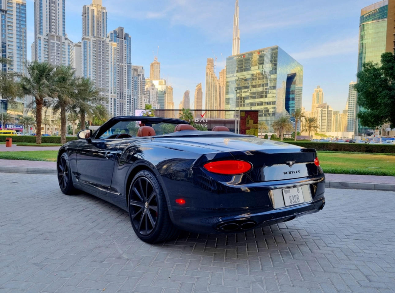 Dark blue Bentley convertible parked in Dubai with skyscrapers in background