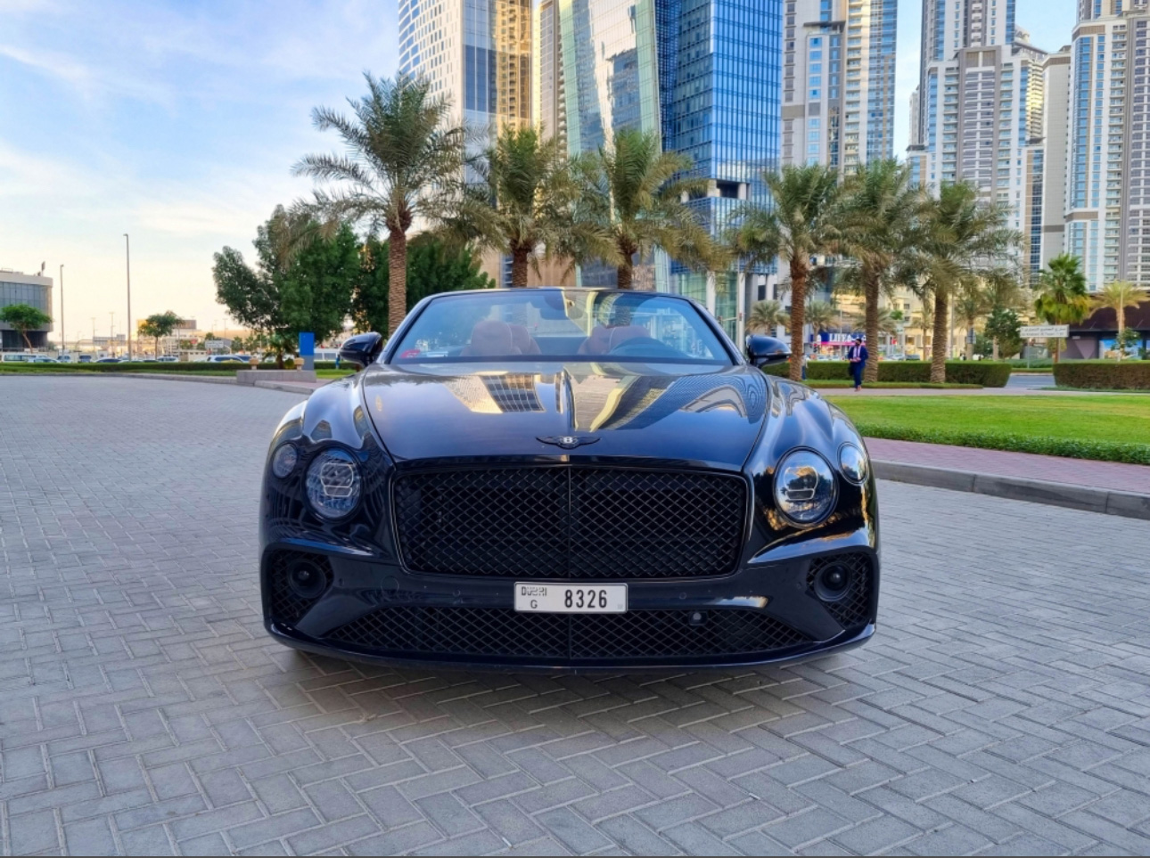 Black Bentley convertible parked in modern urban setting with palm trees