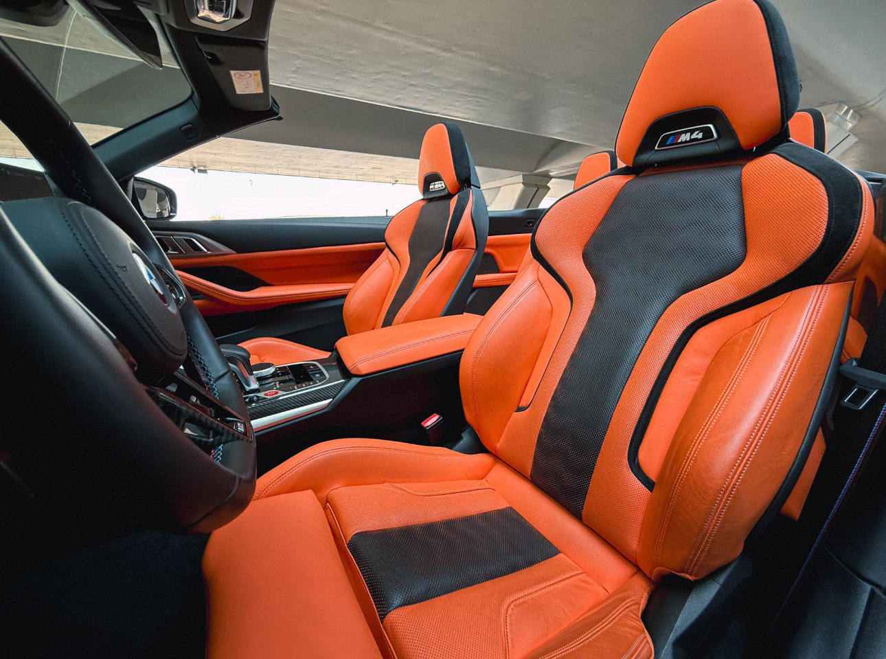 BMW M4 interior with vibrant orange and black sports seats
