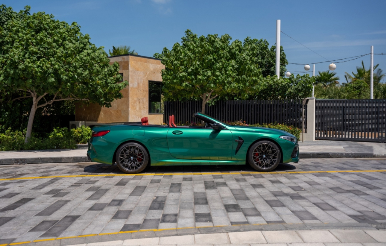 Metallic green convertible sports car parked on geometric stone pavement