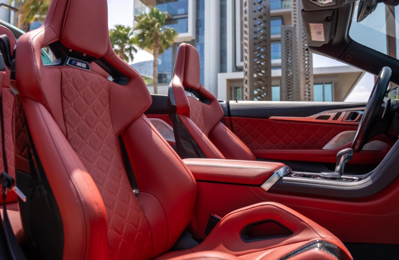 Red leather BMW M3 seats with quilted pattern, urban background