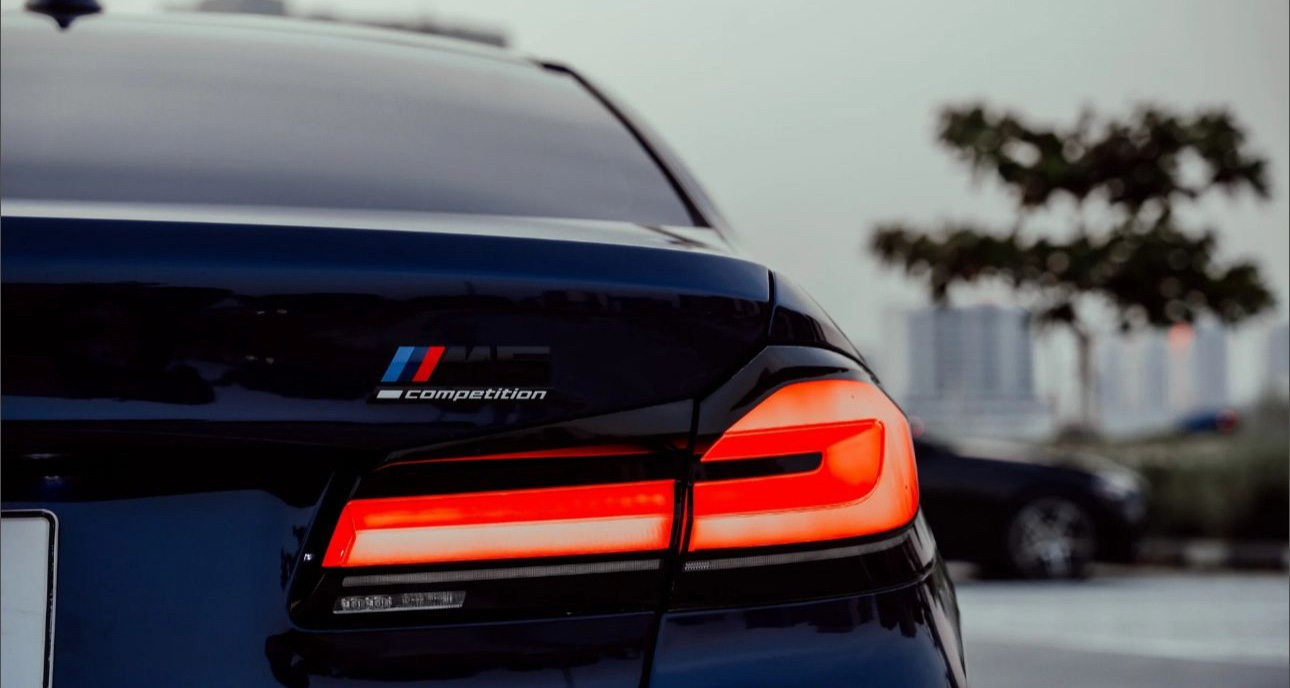 BMW M Competition sedan with glowing red taillight in urban setting