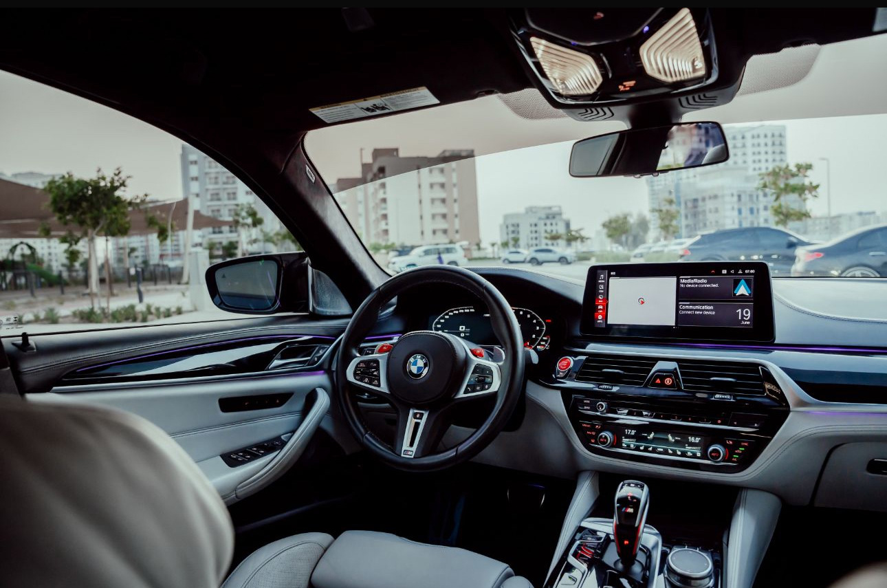 Interior of a modern BMW with digital dashboard and urban parking view