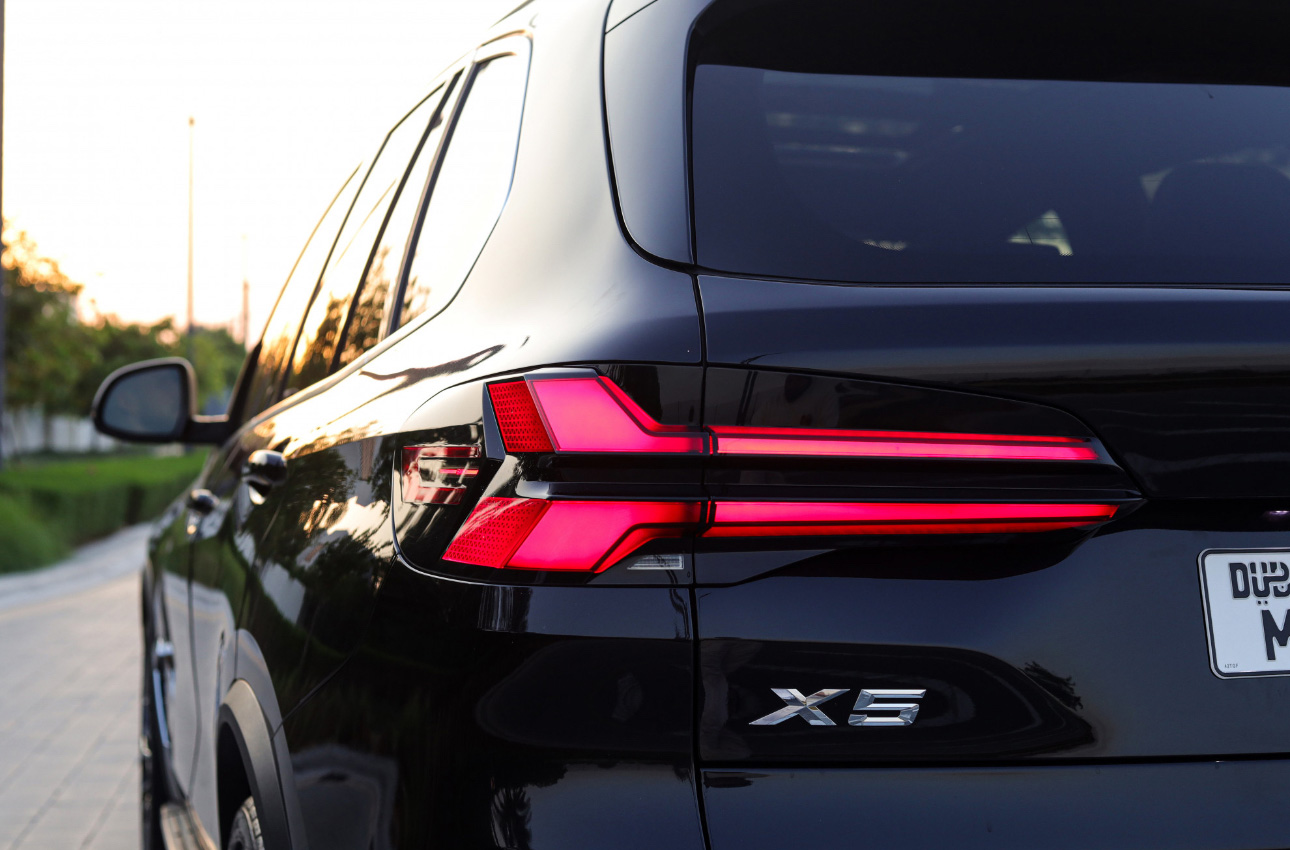 Black BMW X5 SUV rear taillight view at sunset