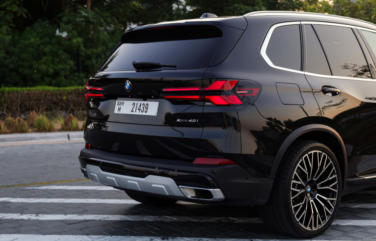 Black BMW X5 SUV with red taillights parked on urban street