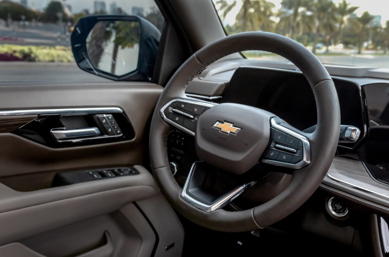 Chevrolet car interior with steering wheel and dashboard, palm trees outside