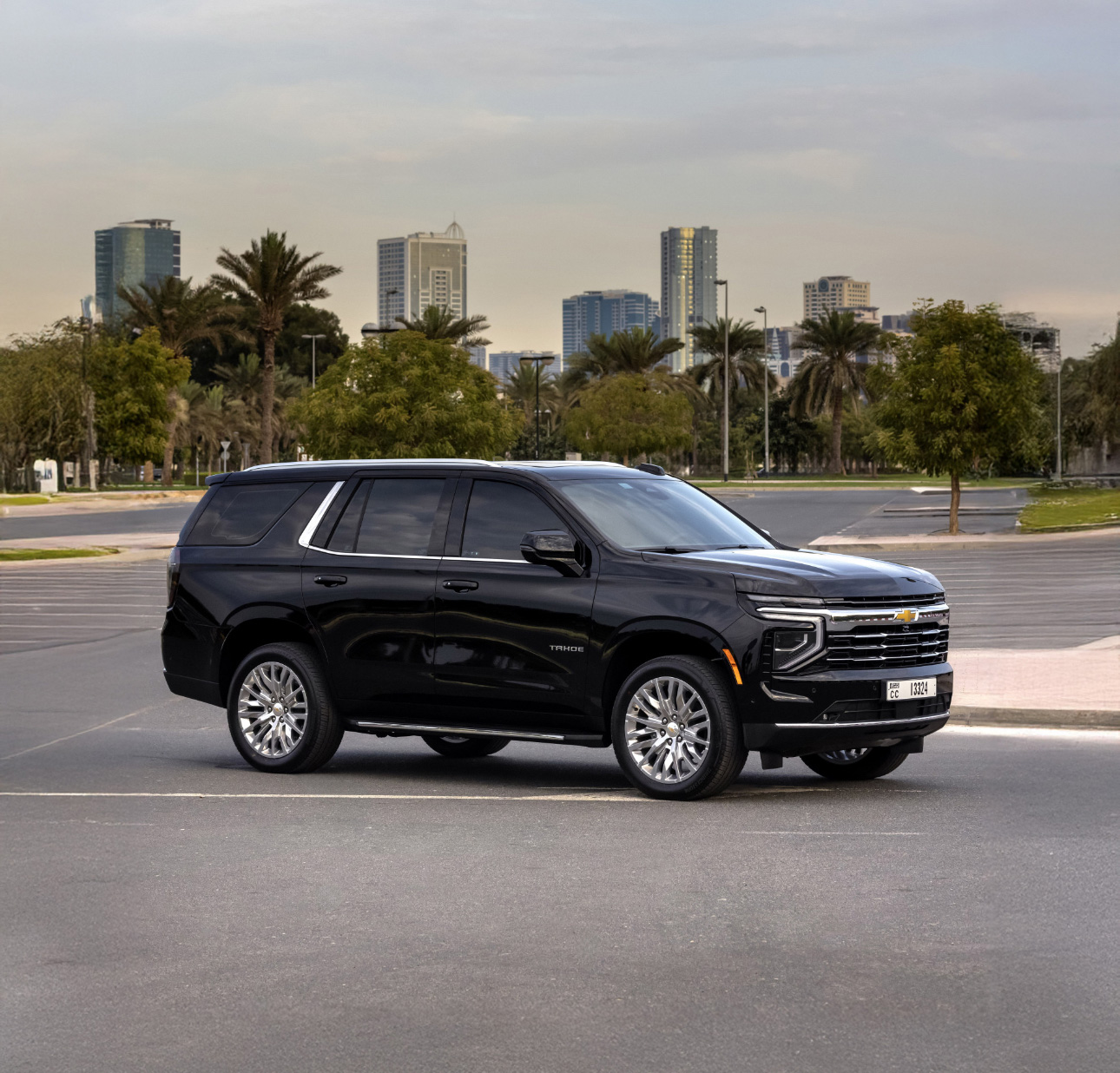 Black Chevrolet Tahoe SUV parked with city skyline and palm trees