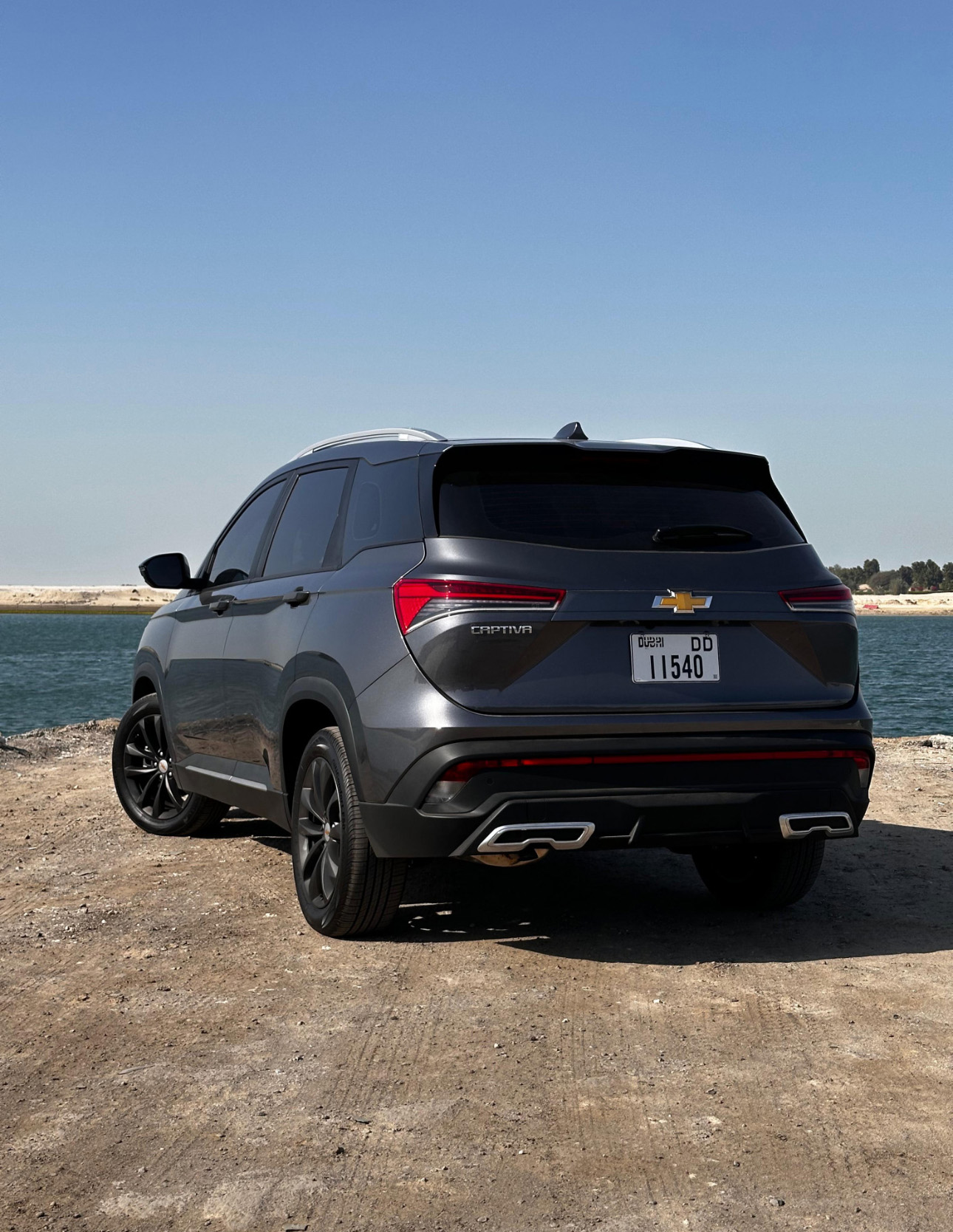 Gray Chevrolet Captiva SUV parked by water on rocky terrain