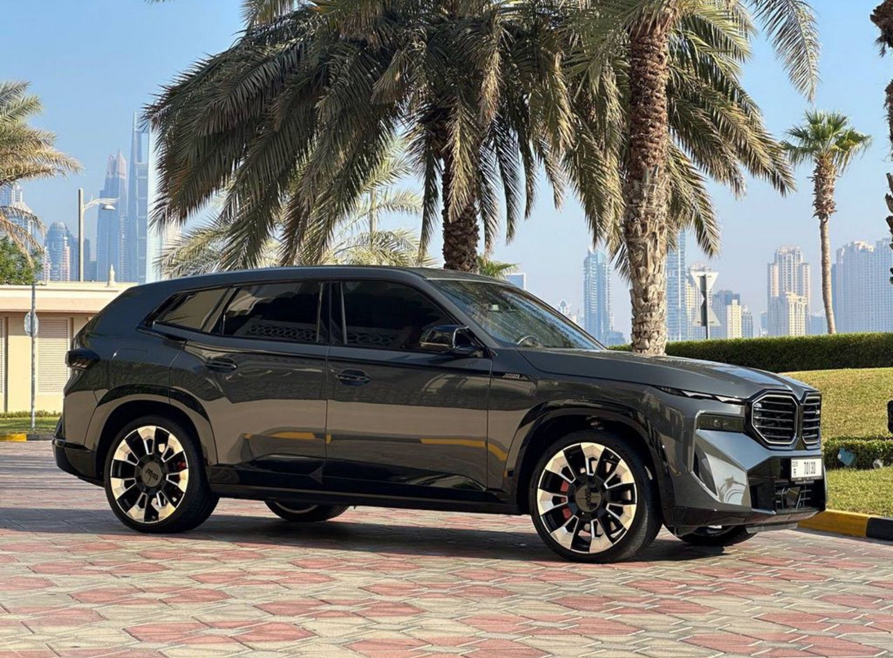Black BMW SUV parked near palm trees with Dubai skyline in background