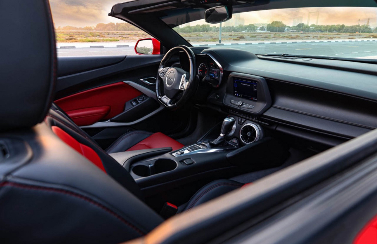 Red and black convertible car interior with open top and dashboard view