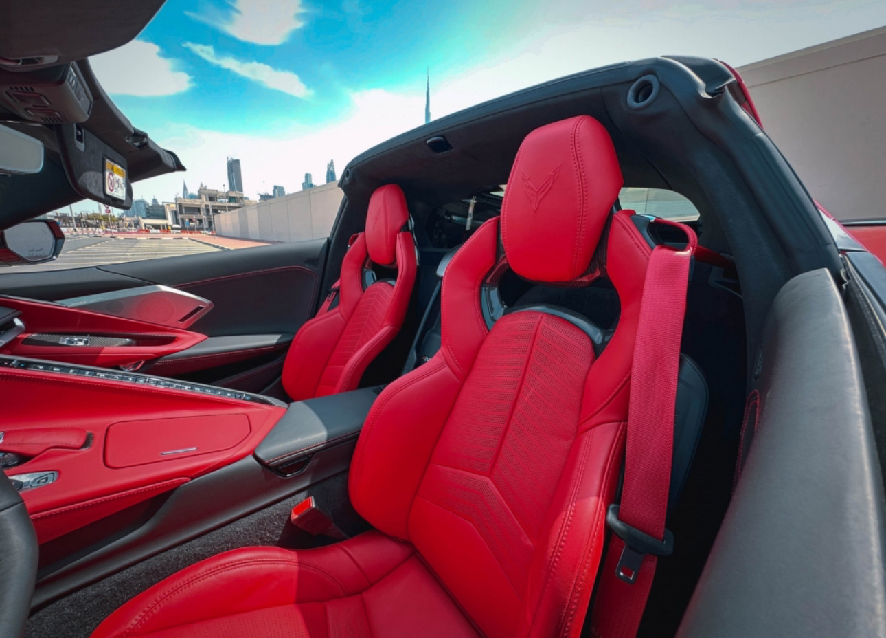 Bright red leather sports car seats with city skyline in background
