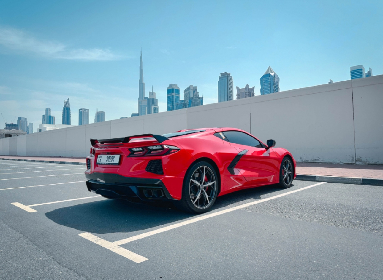 Bright red sports car parked with Dubai skyline in background