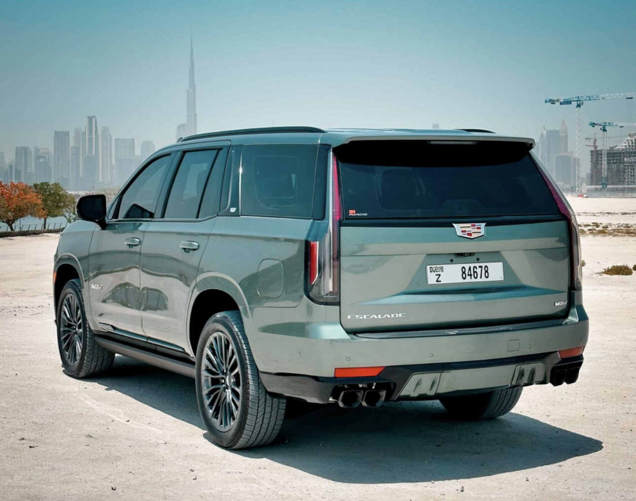 Cadillac Escalade in green, parked with Dubai skyline in background