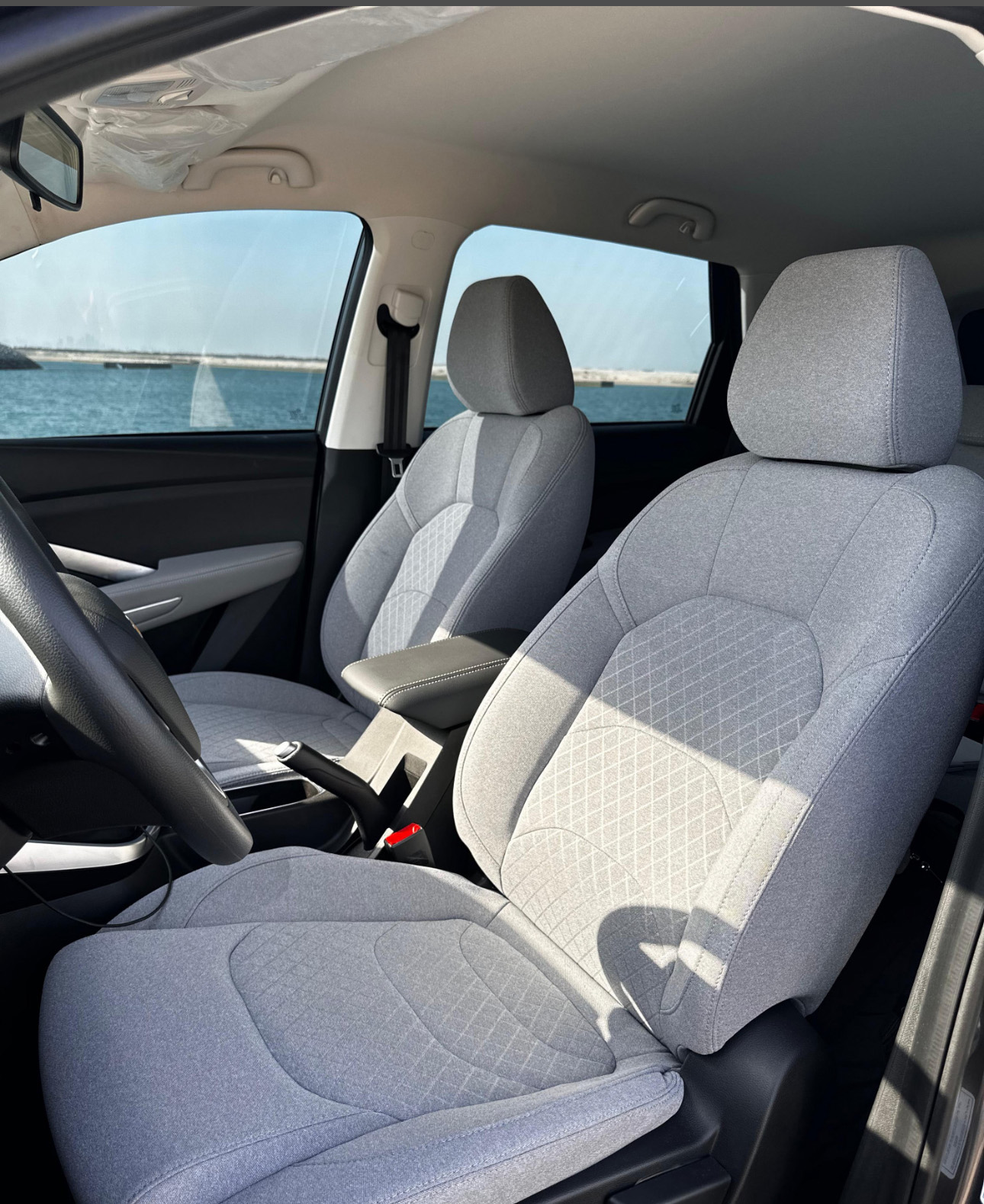 Gray car interior with quilted seats and ocean view through window