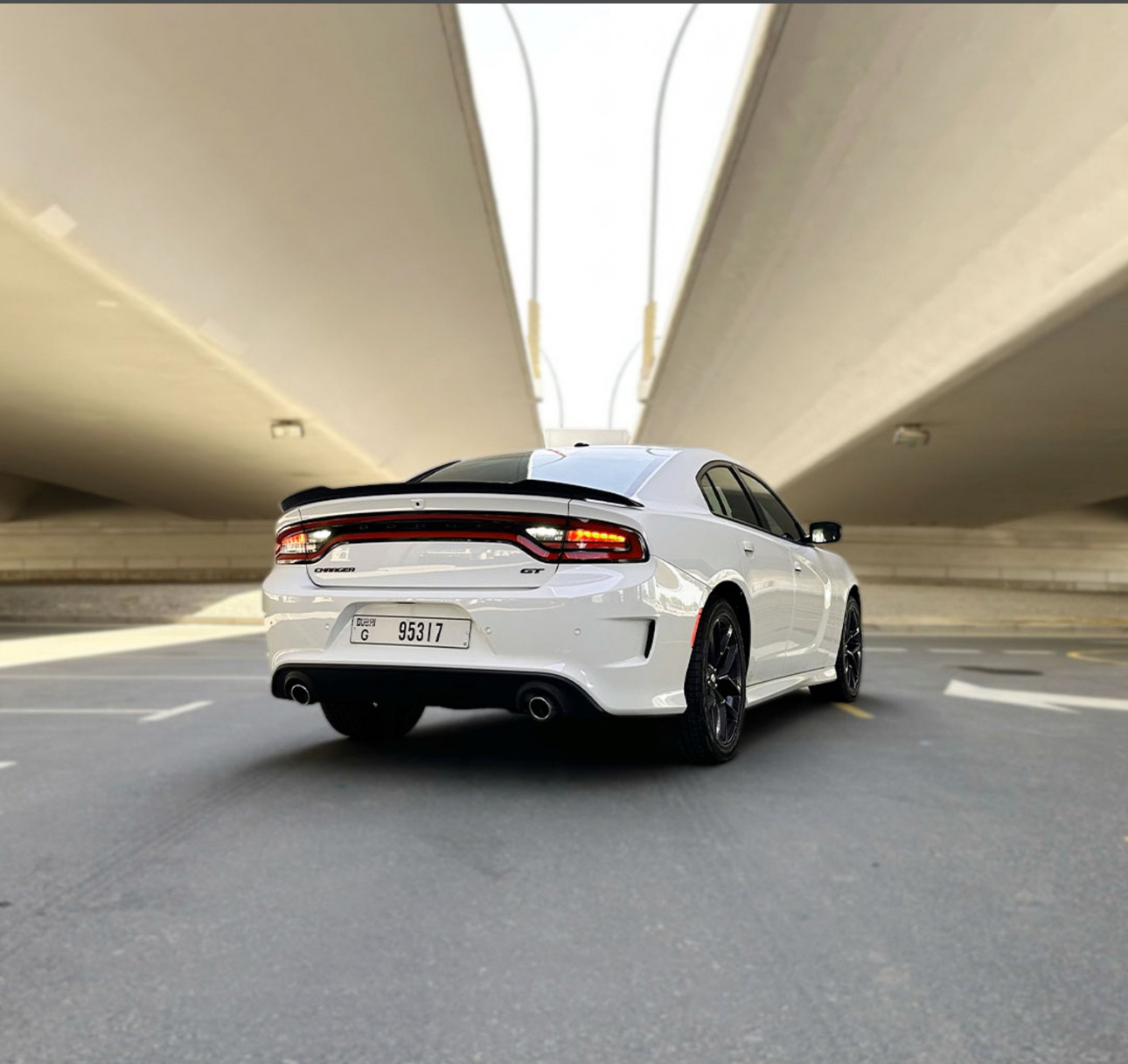 White Dodge Charger GT parked in a minimalist concrete parking structure