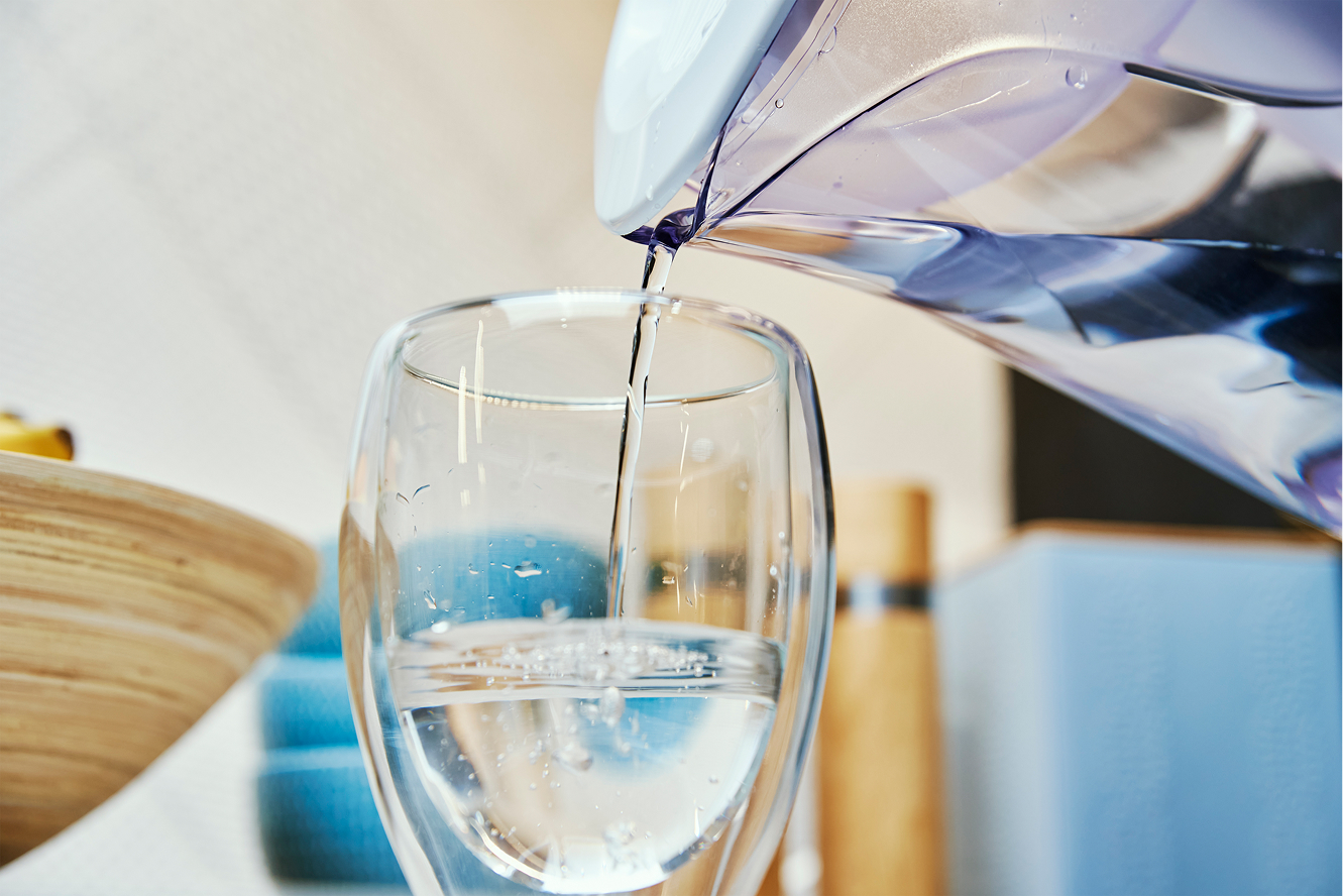 Glass of water being filled, emphasizing hydration for oral health and overall wellness.