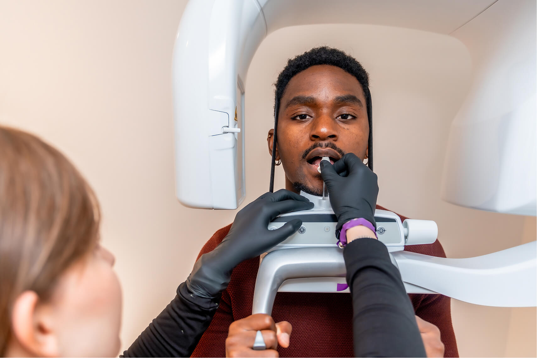 Patient undergoing a panoramic dental X-ray as a technician operates the imaging machine.