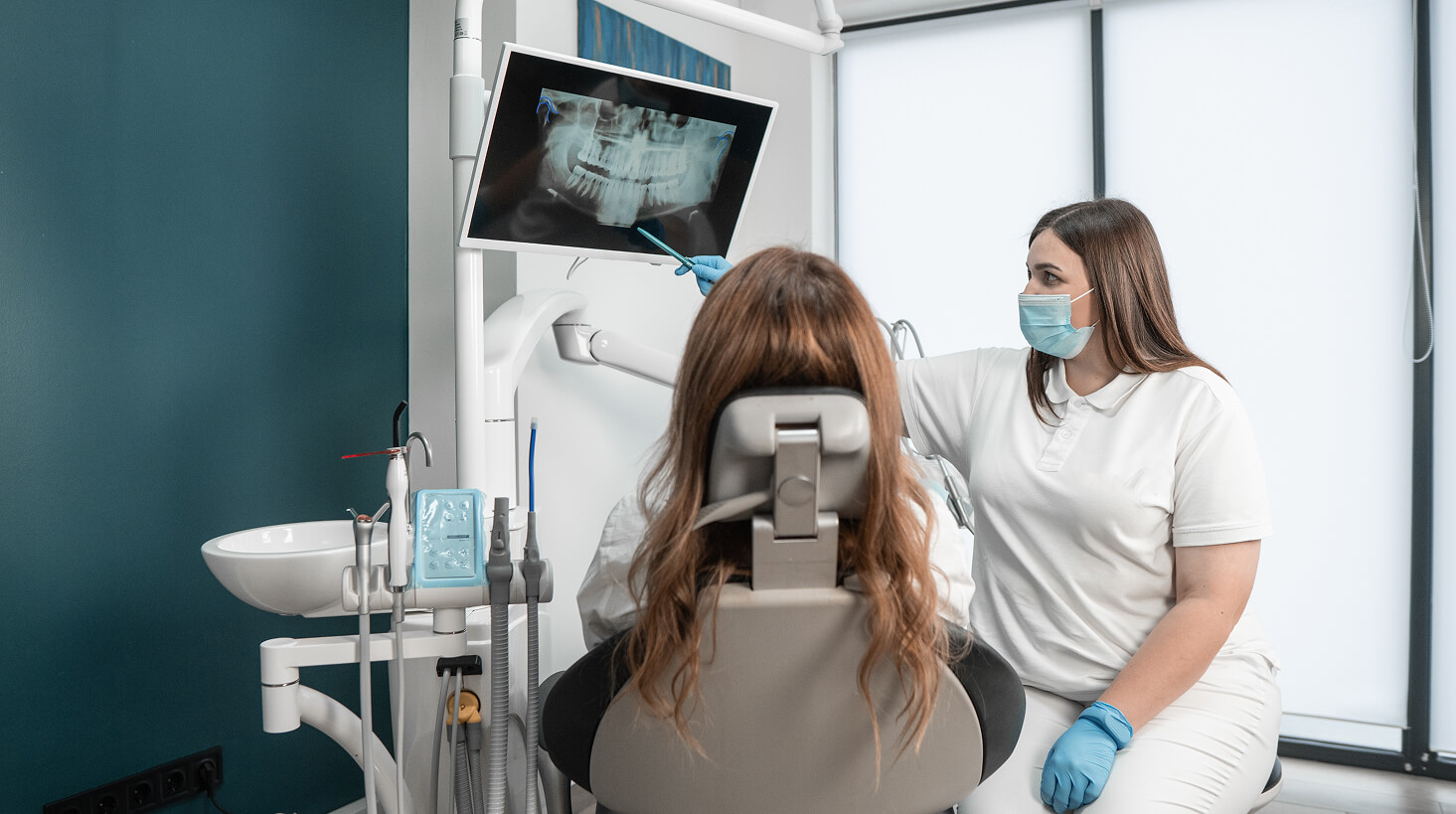 Dental assistant helping a patient inside a modern dental clinic during an exam.