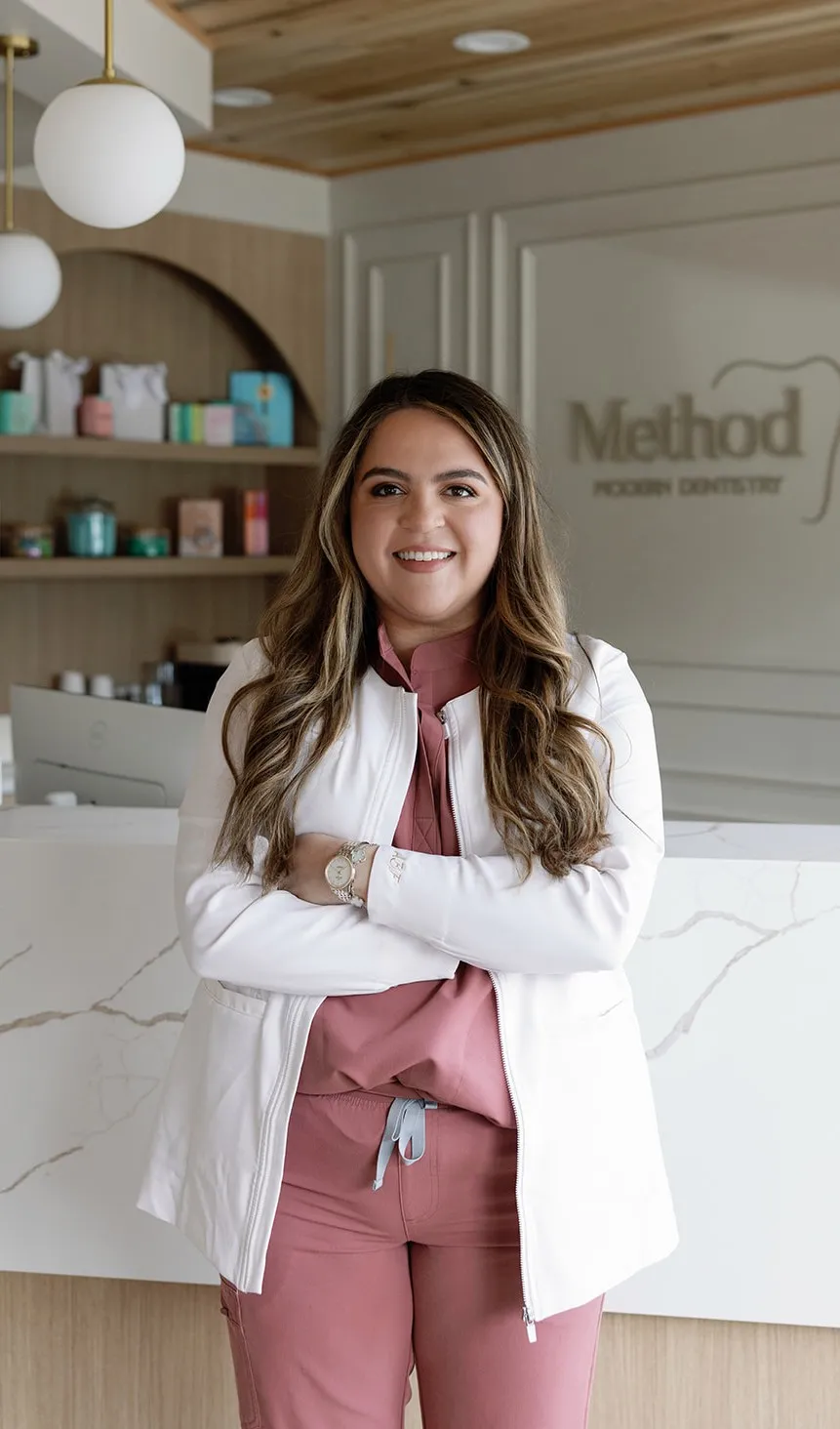 Dr. Alex Franco standing with arms crossed and smiling in front of the Method Modern Dentistry logo at the Alpharetta, GA practice
