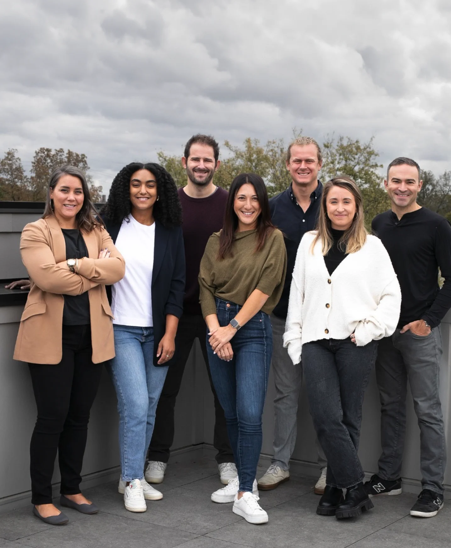 A group of seven House Account team members posing on a rooftop terrace.