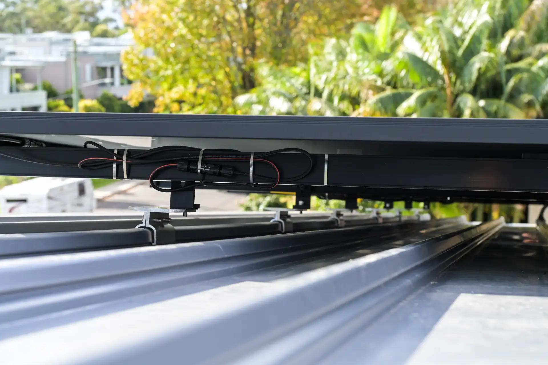 DC solar cables neatly bundled and secured with cable ties along Clenergy mounting rails on a klip-lok metal roof — Solarbank installation