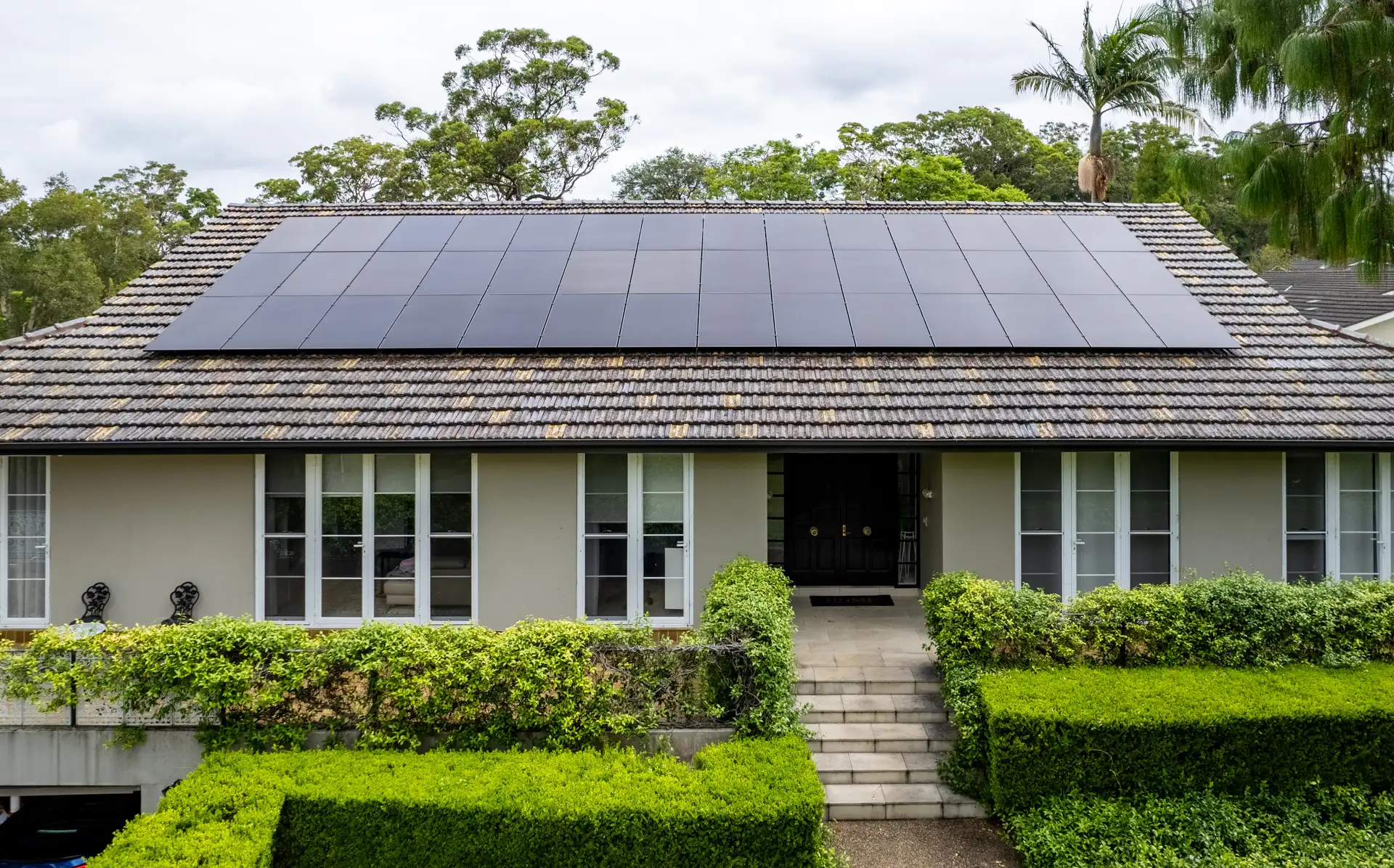 Neatly arranged all-black AIKO solar panels sitting flush and evenly spaced on a terracotta tile roof, demonstrating Solarbank's attention to visual detail — St Ives, Sydney