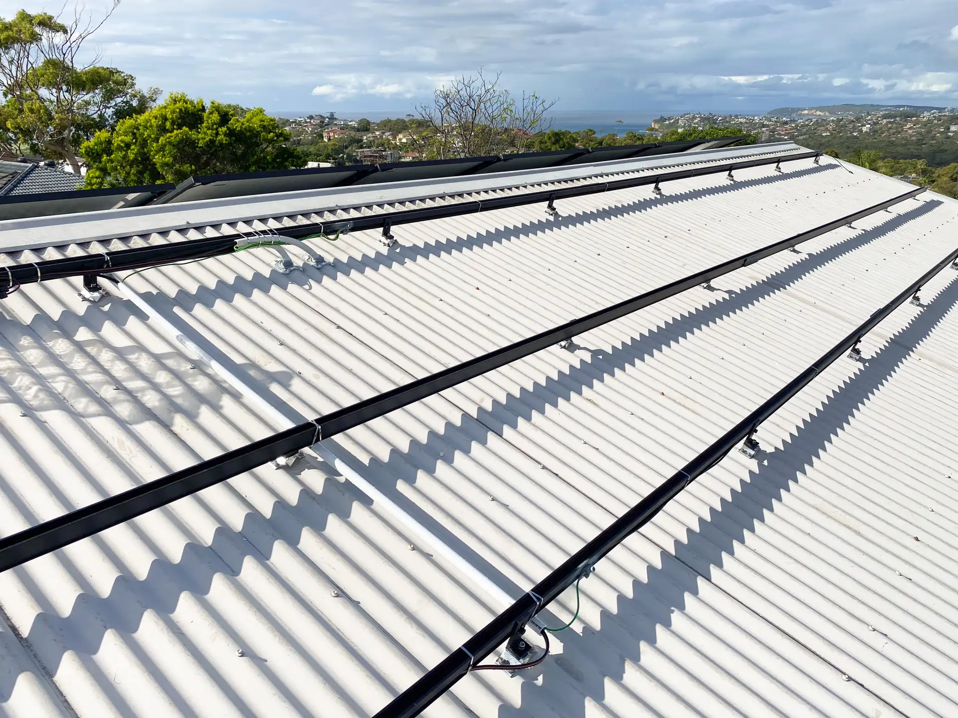 Clenergy mounting rails and solar panels installed on a corrugated iron roof with neatly routed cabling — Solarbank installation, Sydney