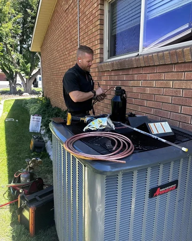 Technician performing an air conditioning tune-up in a residential garden setting