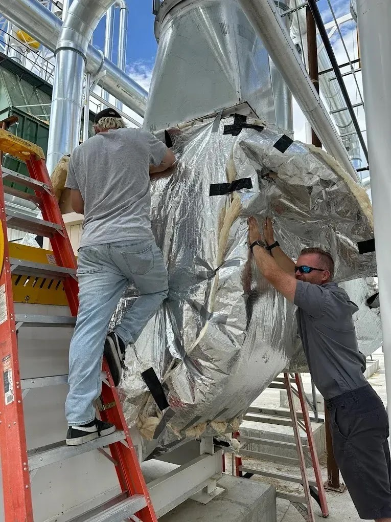 Technician performing HVAC load calculations in a living room with visible insulation materials