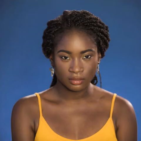 Portrait of a woman with braided hair wearing a yellow spaghetti strap top against a blue background.