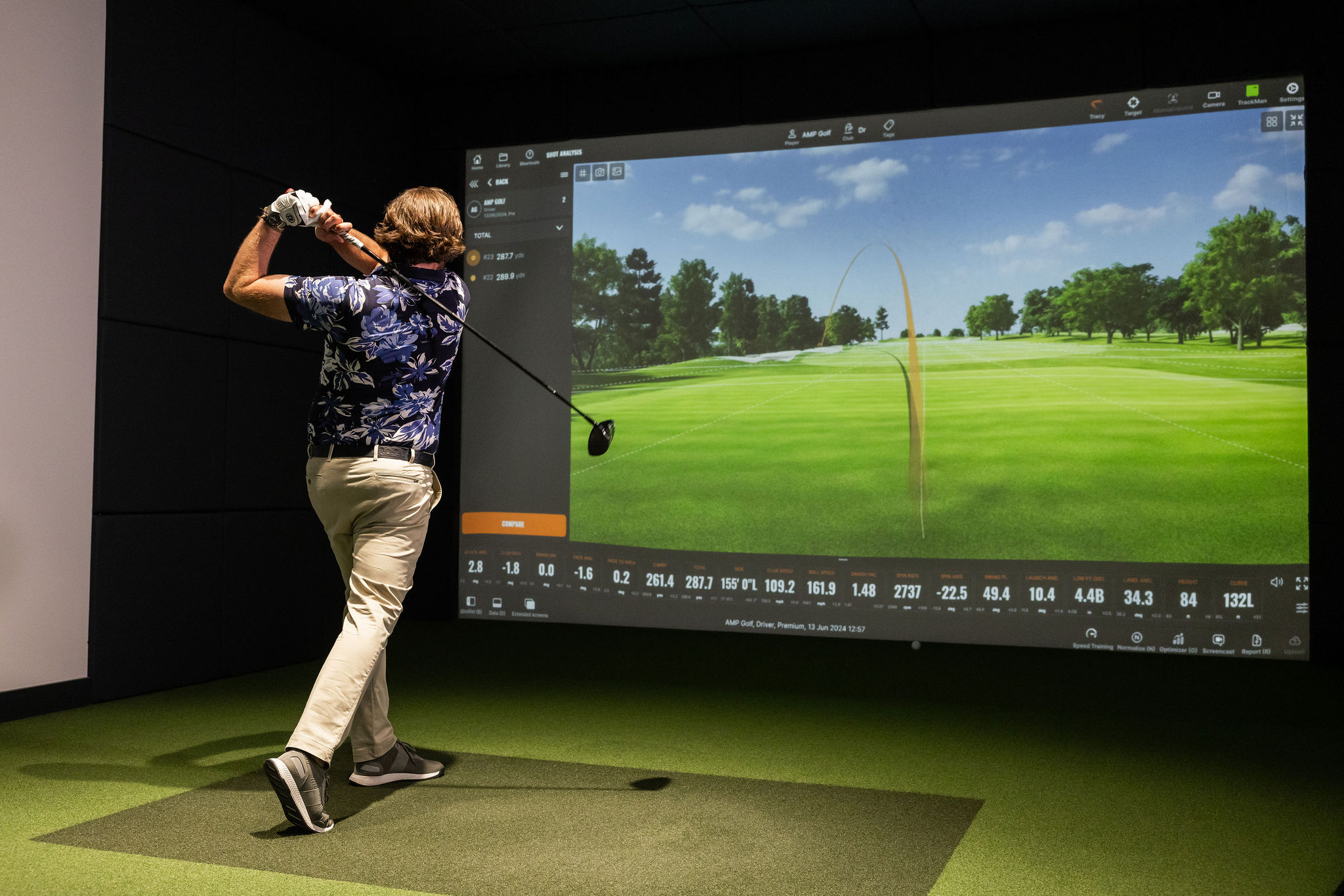 Man swinging a golf club in front of a simulator