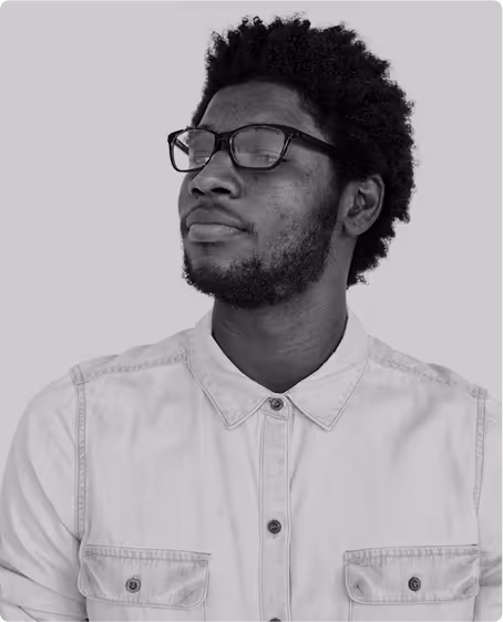 Portrait of a young man with glasses and a beard wearing a light button-up shirt, looking confidently to the side.