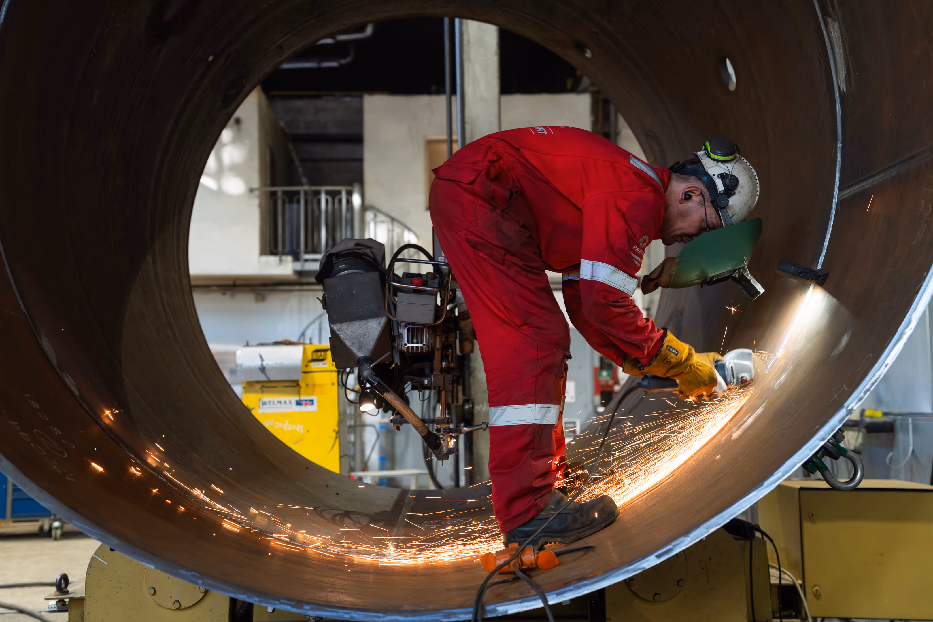 A Parat worker using a saw-like tool to cut materials in an industrial workshop.
