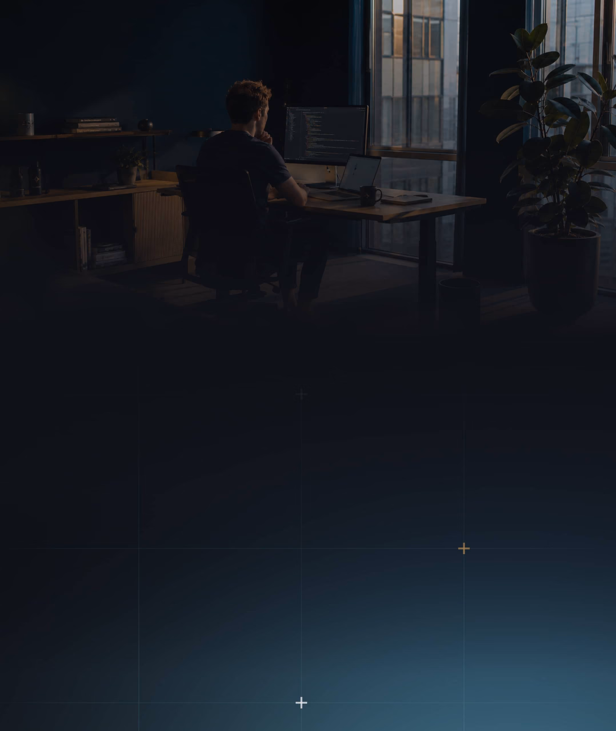 Engineer working late at a desk lit by a single monitor