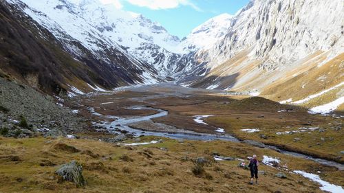 Blick in ein weites Tal. Ein Fluss fliesst durch das Tal, die Berge sind verschneit.