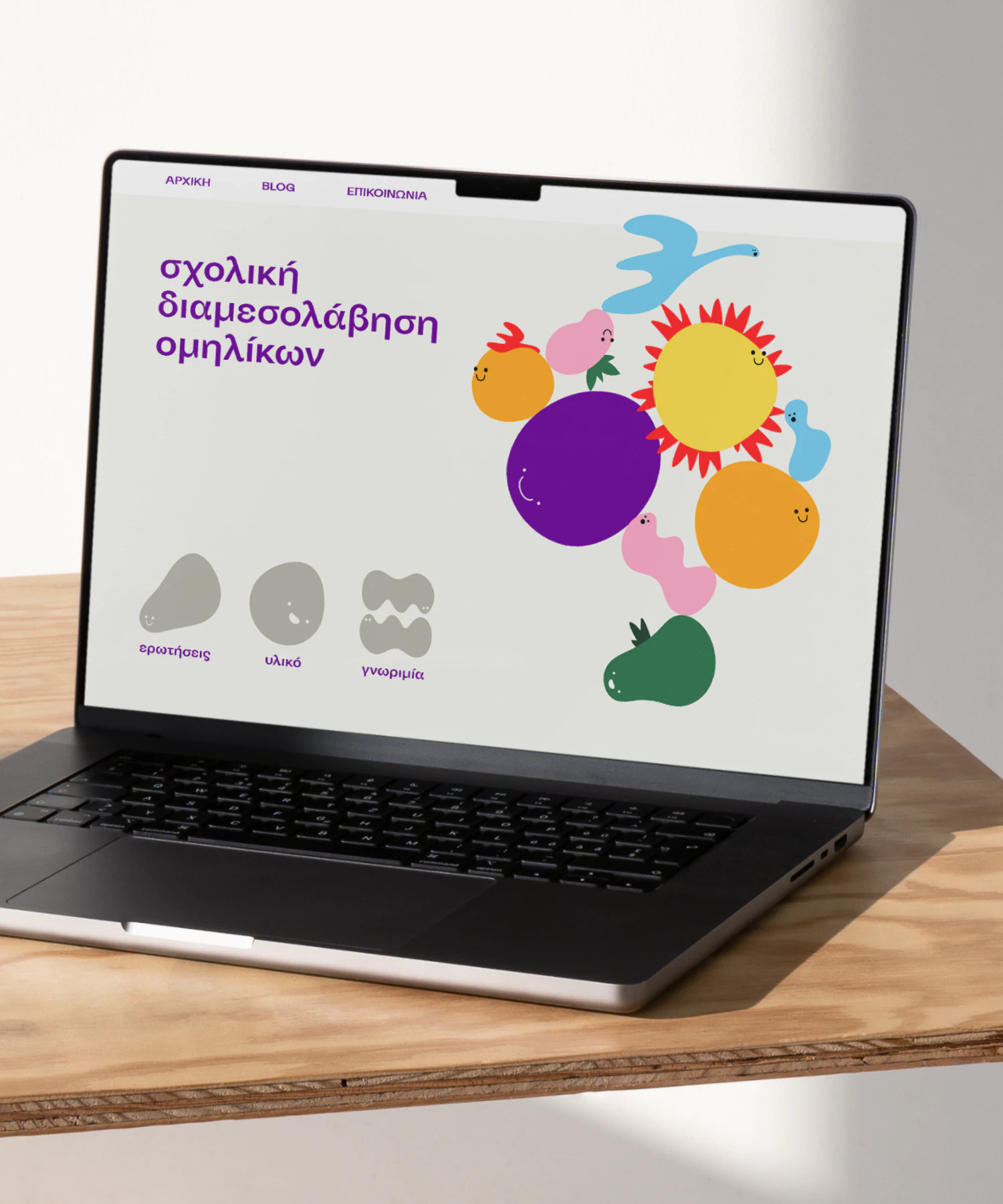 Laptop displaying playful Greek website with colorful character illustrations for school mediation project